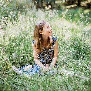 A photo of Thea Caine sitting down in the long grass