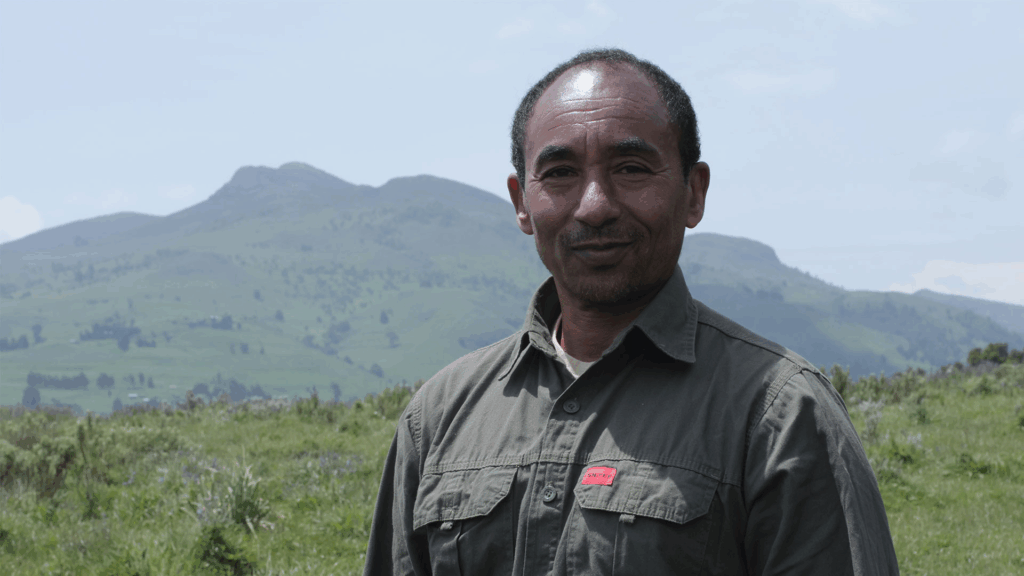 Kumara Wakjia, stood in front of a mountain, looking at the camera